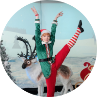 Santa's elf dancing in front of reindeer in Santa's grotto