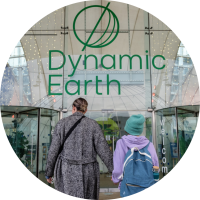 Parent and child holding hands walking towards Dynamic Earth entrance doors.